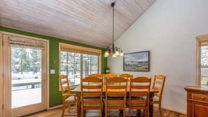 A dining area with a wooden table and chairs, a hanging light fixture, and a painting on the wall. - BIGS07 - Perfect Family Home in Sunriver, Room for All (Sunriver)