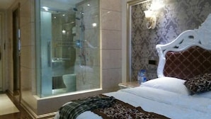 Une chambre d’hôtel moderne dotée d’une douche en verre, d’un grand lit avec une literie à motifs et d’un mur décoratif.