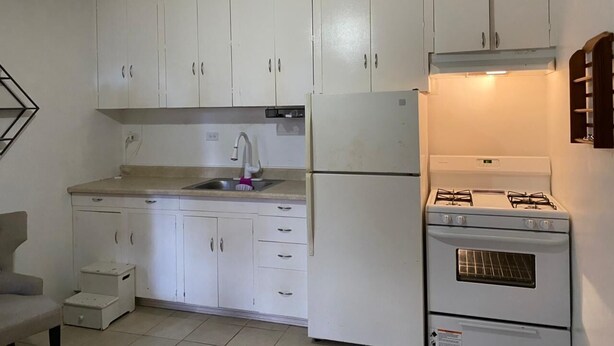 A compact kitchen with white cabinets, a sink, a refrigerator, and a stove. - 5mins to the beach, 2mins fr airport and mins fr restaurants,malls and hospitals (Tamuning)