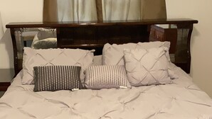 A bed with a white quilted bedspread, two pillows, and a wooden headboard. - 5mins to the beach, 2mins fr airport and mins fr restaurants,malls and hospitals (Tamuning)
