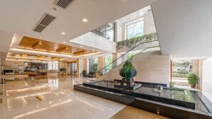 A modern hotel lobby with a central water feature, a staircase, and a reception area. - Pasonda Hotel Foshan (Foshan)