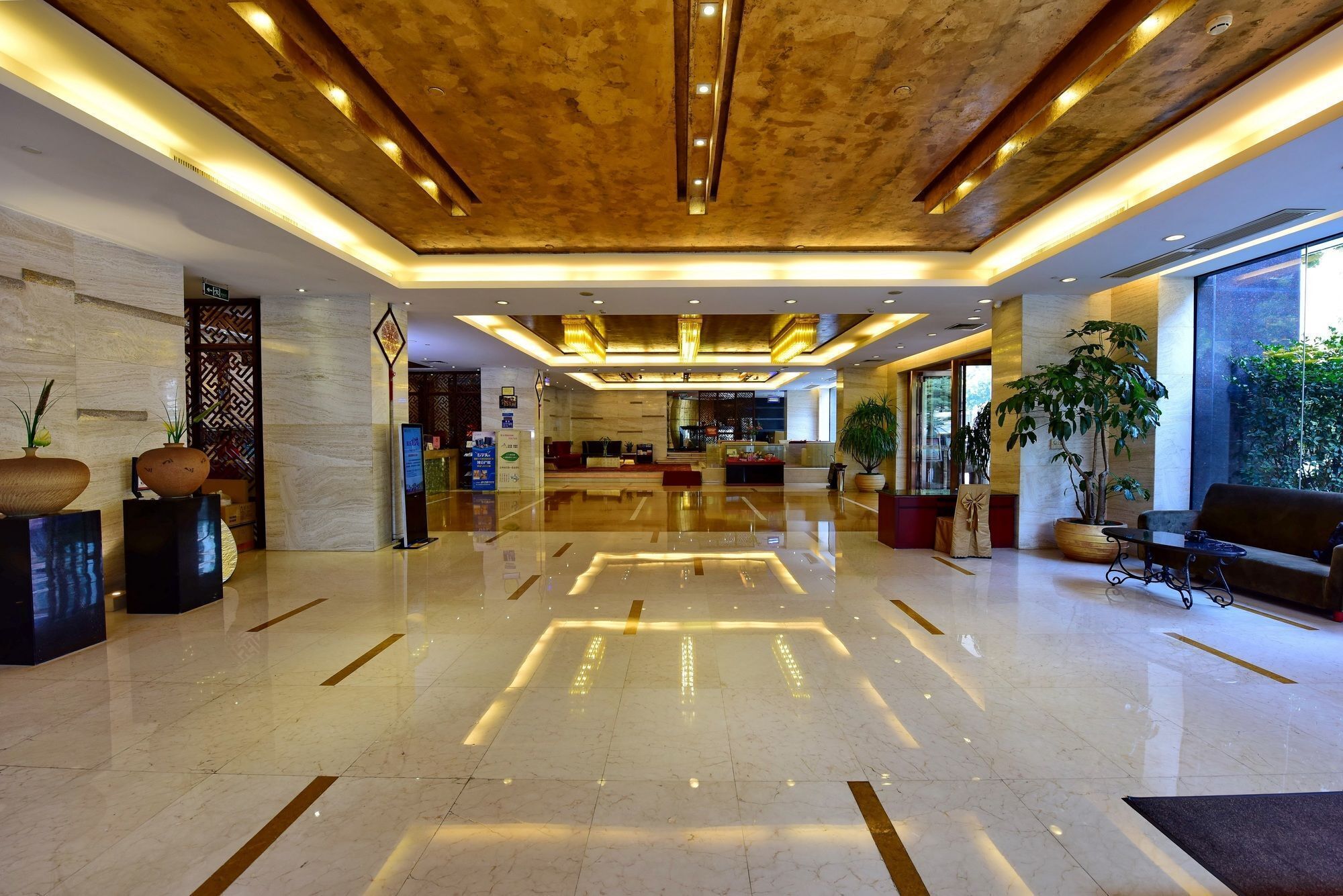 A spacious lobby with a polished marble floor, a reception desk, and a seating area with sofas.