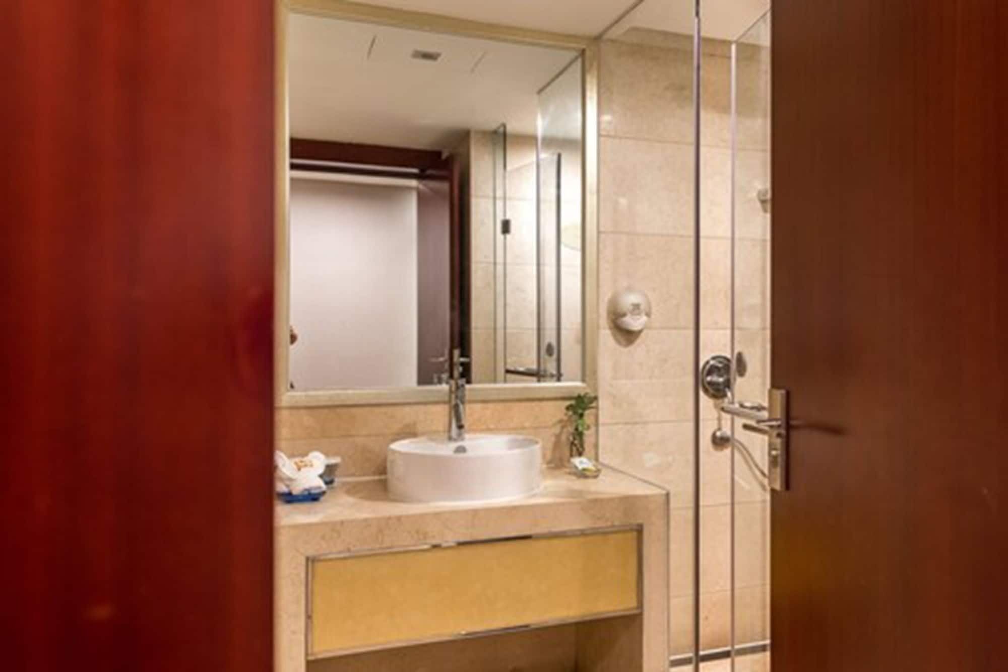Un baño con lavamanos, espejo y zona de ducha.