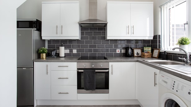 A modern kitchen with white cabinets, a built-in oven, a dishwasher, and a microwave. - Refurbished Belfast Home, 10 mins from centre with parking! (Belfast)
