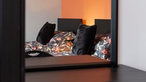A bed with floral bedding and black pillows, a bedside table, and a chair. - Refurbished Belfast Home, 10 mins from centre with parking! (Belfast)