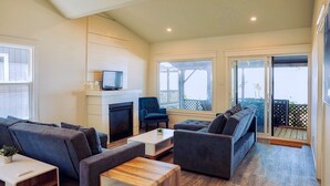 Un salon spacieux doté d’une cheminée, de sièges confortables et de grandes fenêtres offrant une vue sur l’extérieur.