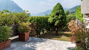 A garden with potted plants, a wooden fence, and a view of mountains. - Feel at Home - LA TORRICELLA (LOVERE)