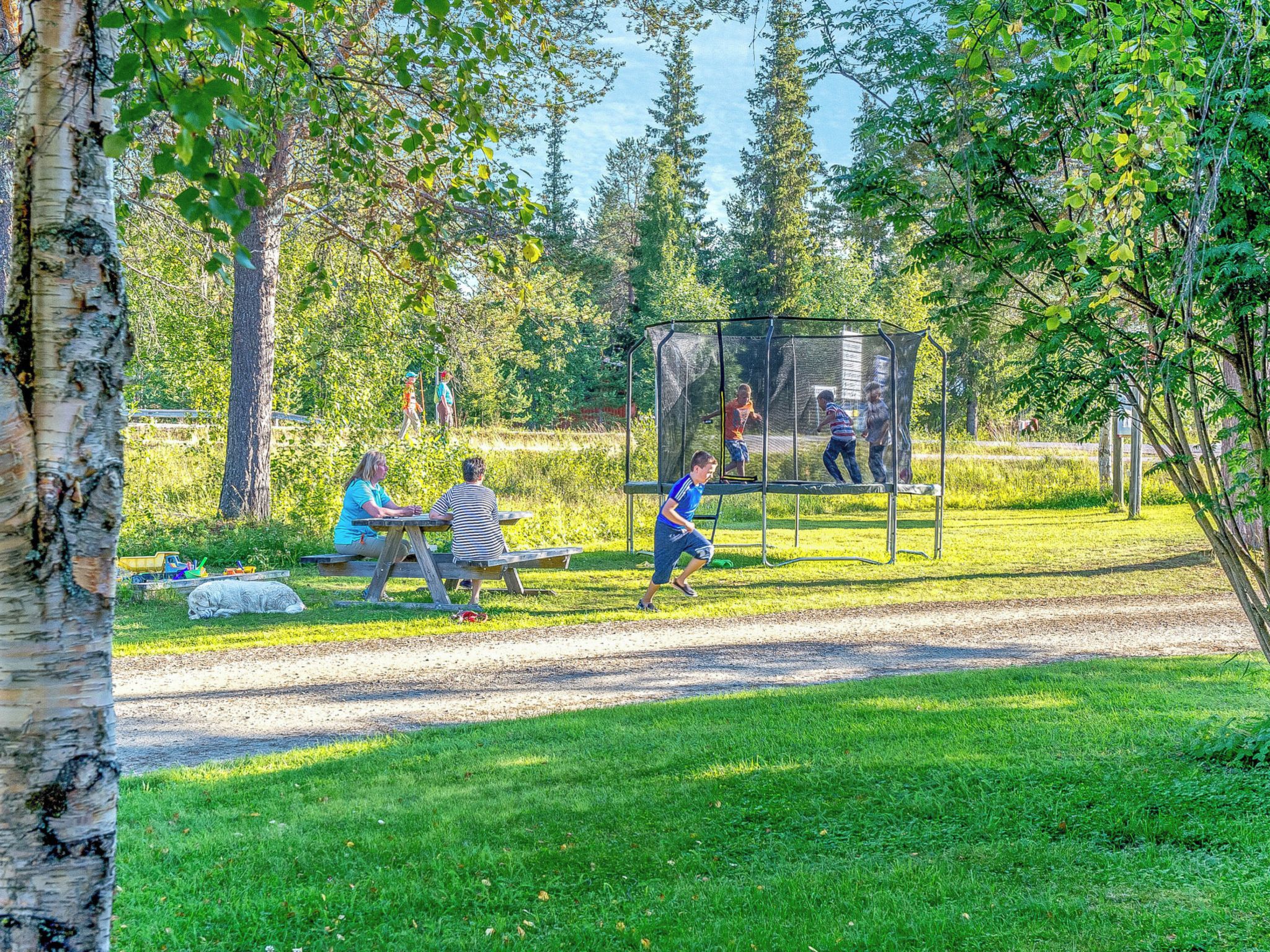 A park with a playground, picnic tables, and a dirt path.