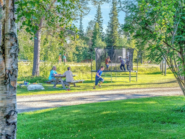 A park with a playground, picnic tables, and a dirt path.