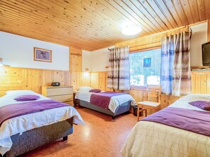 A room with three beds, wooden walls, a window with curtains, a television, and a small table. - Vacation home Pajula by Interhome (Äkäslompolo)