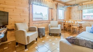 A cozy cabin interior with wooden walls, a dining area, and seating arrangements.