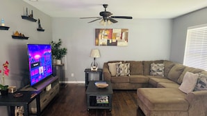 Ein Wohnzimmer mit Flachbildfernseher, Deckenventilator, Sofa und Couchtisch.