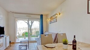 A dining area with a table set for two, a television, and a sofa. - Résidence Soko Eder by Interhome (Saint-Jean-de-Luz)