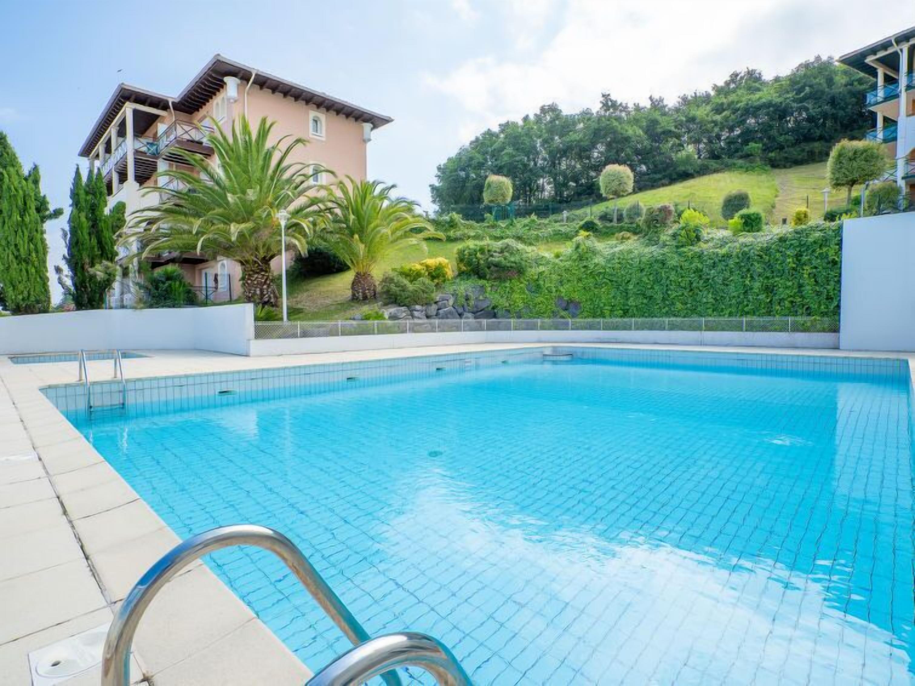 A swimming pool with a clear blue water surface, surrounded by a white tiled deck.