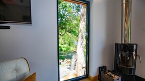Una habitación con un ventanal grande, un sofá, una chimenea y una cesta de mimbre.