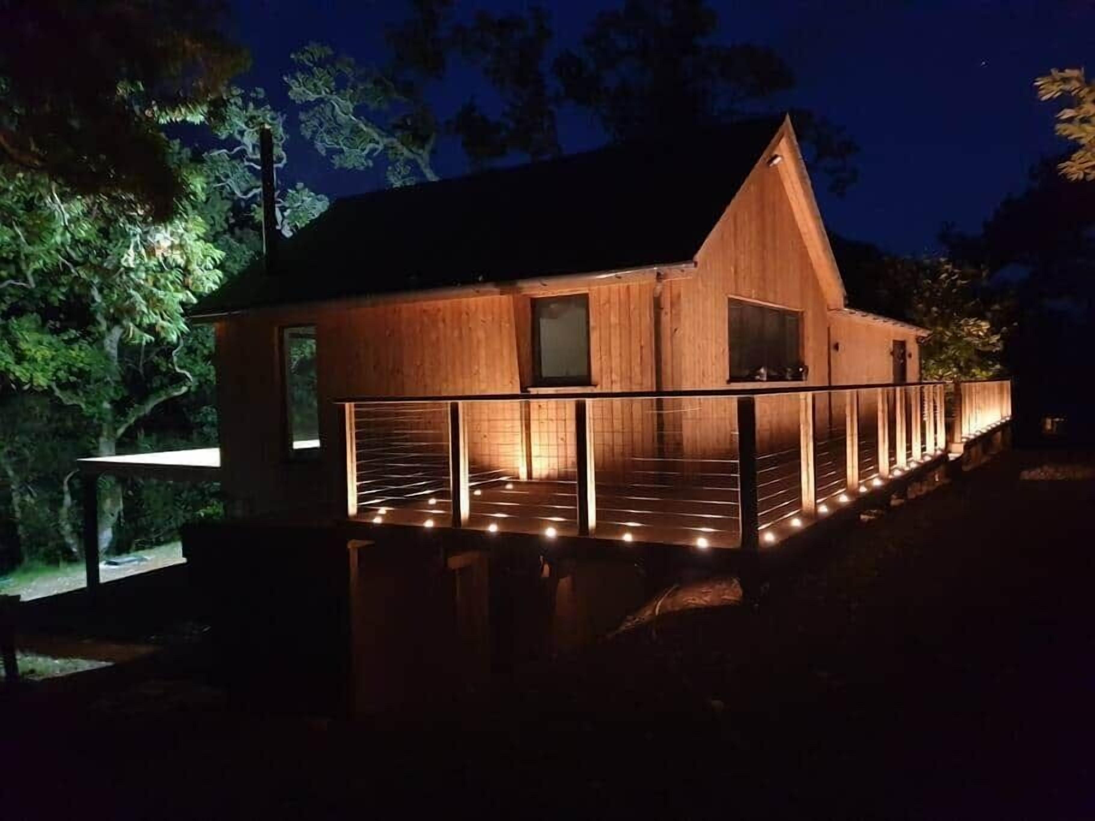 Une cabane en bois dotée d’un balcon, entourée d’arbres.