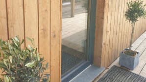 Entrada de un edificio de madera con puerta de vidrio, un cartel que dice 'Tresillian Lodge' y una pequeña planta en maceta a un lado.