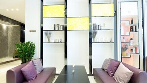 A modern lobby with two sofas, a coffee table, and a bookshelf with decorative items. - Lavande Hotel Shenzhen Baoan Haiya Binfen City (Shenzhen)