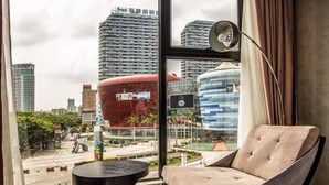 A modern hotel room with a large window offering a city view, a comfortable sofa, a small side table, and a floor lamp. - Lavande Hotel Shenzhen Baoan Haiya Binfen City (Shenzhen)