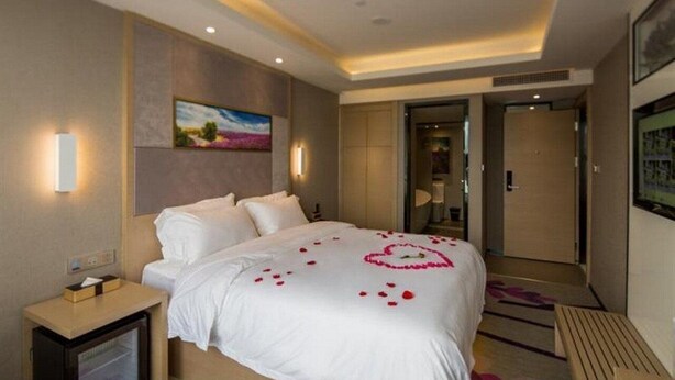 A hotel room with a large bed, a nightstand, a television, and a painting on the wall. - Lavande Hotel Shenzhen Baoan Haiya Binfen City (Shenzhen)