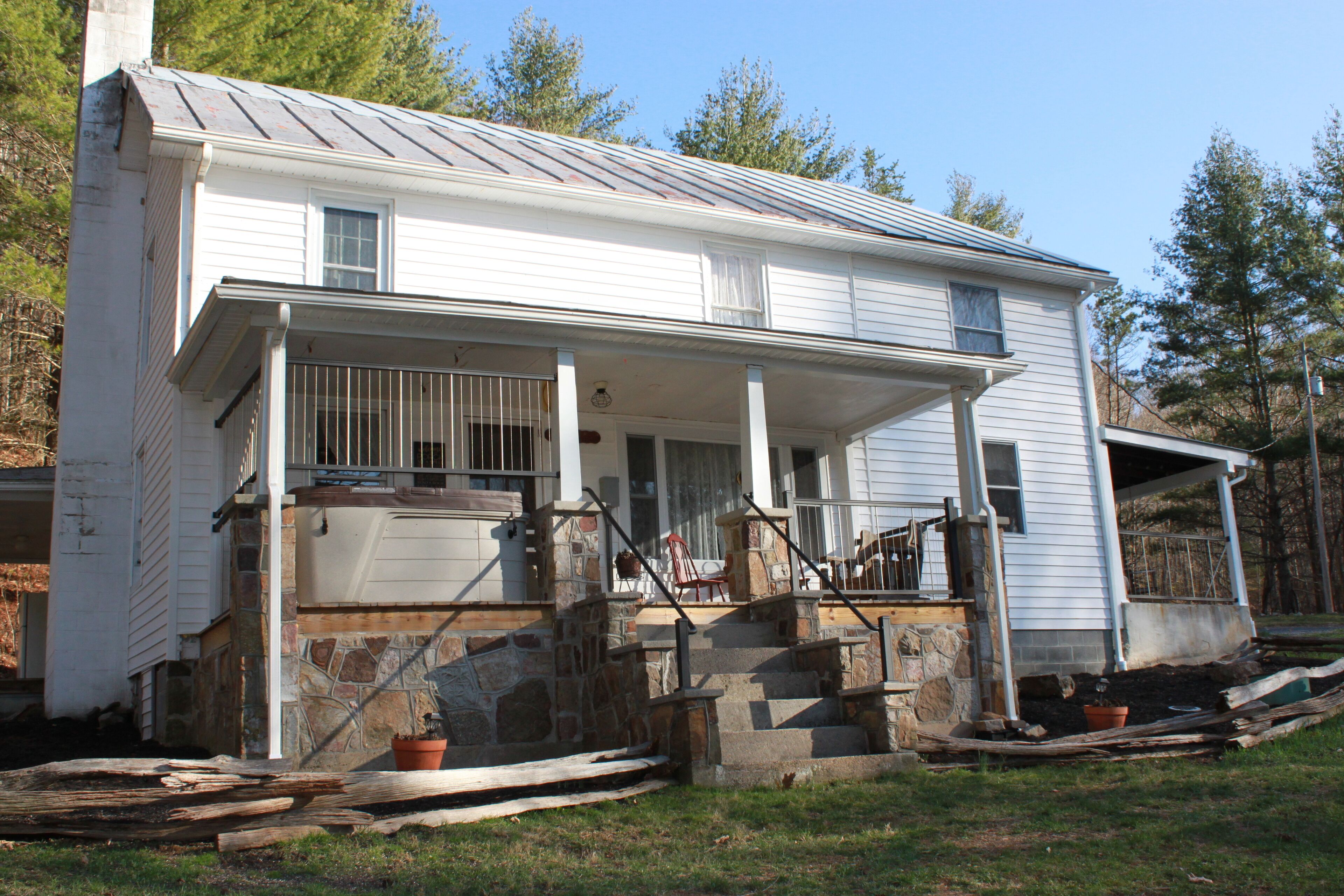 A two-story house with a porch, stone steps, and a chimney.