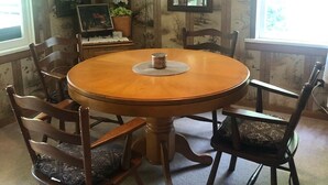 A wooden dining table with a central candle holder, surrounded by six wooden chairs with cushioned seats.