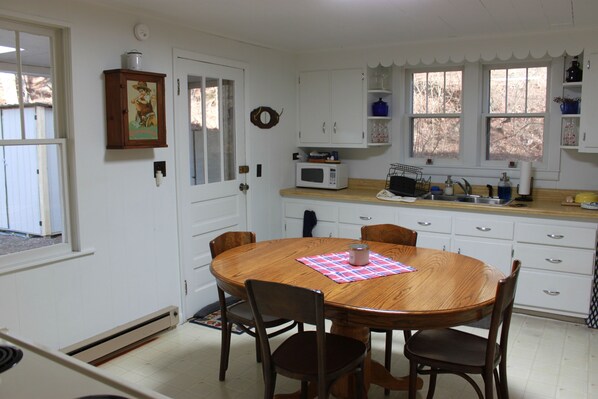 A kitchen with white cabinets, a wooden dining table, and a microwave.