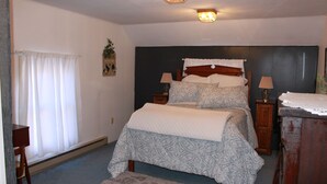 A bedroom with a bed, bedside tables, a lamp, a dresser, and a window with curtains.