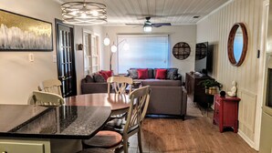 A dining area with a table and chairs, a sofa set, a ceiling fan, and a large mirror. - Zen Retreat w/ Hot Tub & Private Pool - Near Beach! (Panama City Beach)
