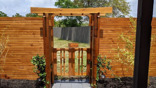 A wooden gate with a small wooden box on top, surrounded by a wooden fence and plants. - Zen Retreat w/ Hot Tub & Private Pool - Near Beach! (Panama City Beach)