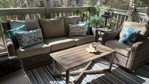 A sunlit outdoor seating area with a sofa, armchairs, and a coffee table.