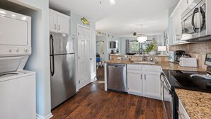A modern kitchen with white cabinets, stainless steel appliances, and a granite countertop.