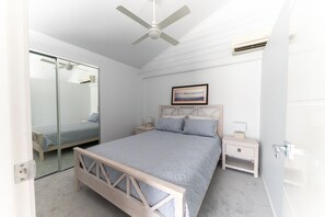 Relax in a serene bedroom with a large bed, bedside table, and ceiling fan.