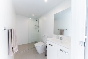 Enjoy a refreshing shower in the sleek bathroom with a glass-enclosed shower, toilet, and vanity.