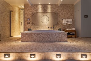 A modern bathroom with a large bathtub, a wall-mounted towel rack, and a textured wall design. - Private Luxury Pool & Spa Retreat – Great Location (Boynton Beach)