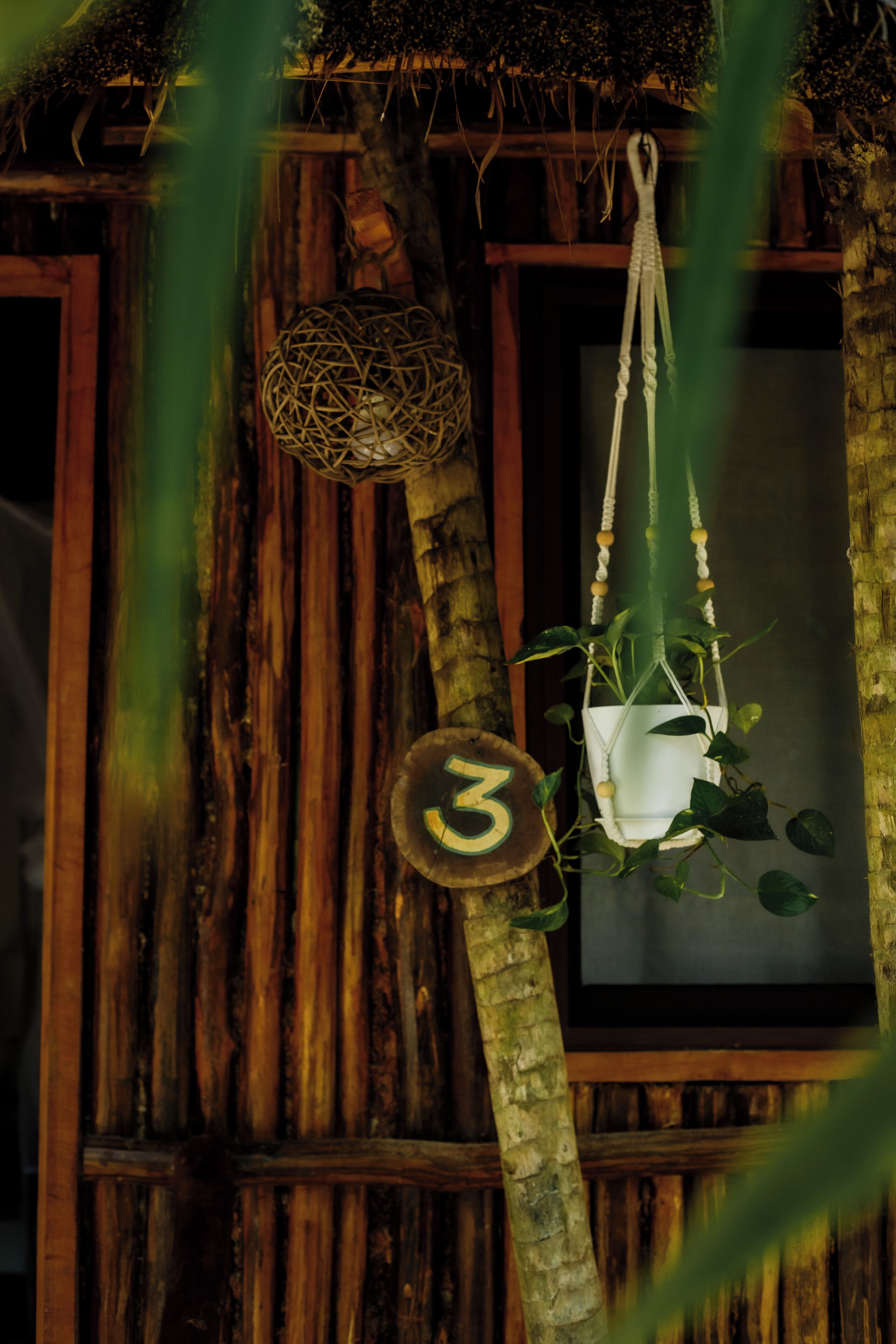 A rustic wooden structure with a hanging plant in a white pot and a decorative hanging item.