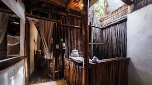 A narrow, wooden-walled bathroom with a sink, towel rack, and a small shelf. - Eco.Bañitas (Tulum)