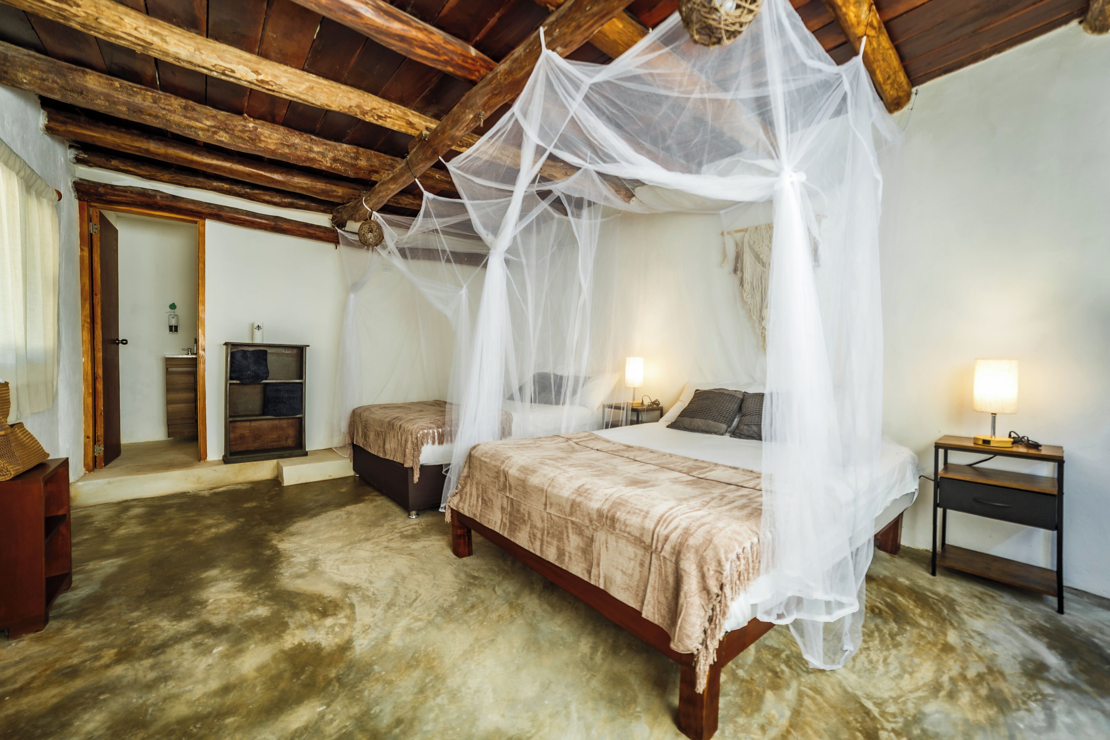 Een slaapkamer met een hemelbed, nachtkastje, bijzettafeltje en een kledingkast.