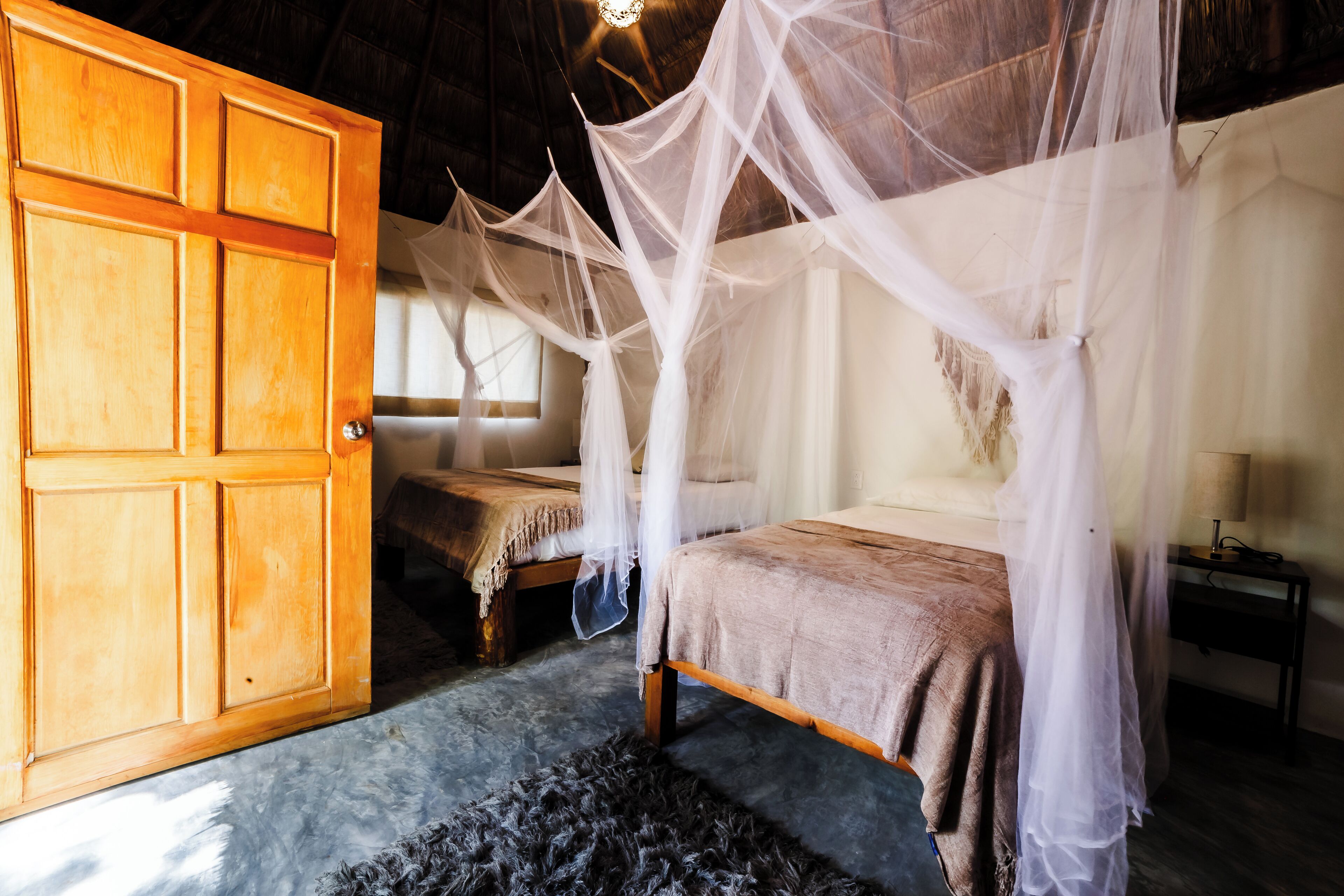 Una habitación con puerta de madera, una cama con dosel y una pequeña mesa.