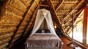 A bed with a canopy in a room with a thatched roof. - Eco.Bañitas (Tulum)