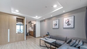 A modern living room with a grey sofa, a coffee table, and a kitchen area in the background. - Daecheon 2278 Resort (Boryeong)
