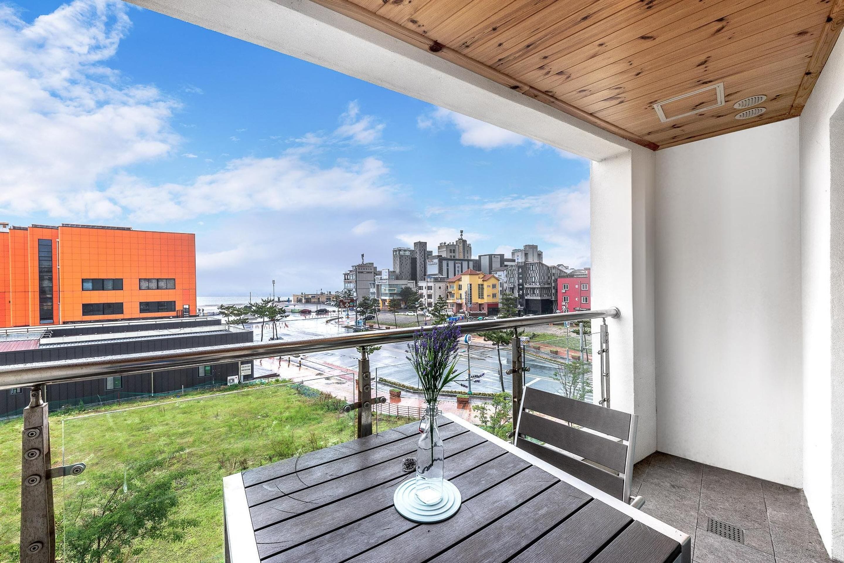 Un balcón con vistas a un paisaje urbano, incluyendo un edificio naranja destacado y diversas otras construcciones.
