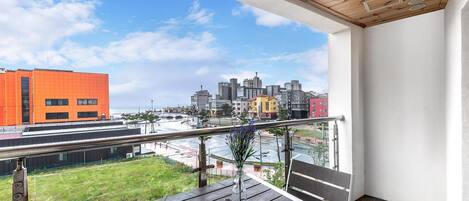 Un balcón con vistas a un paisaje urbano, incluyendo un edificio naranja destacado y diversas otras construcciones.