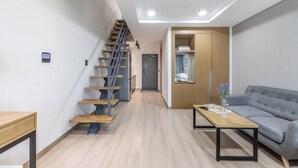 A modern apartment with a wooden staircase, a gray sofa, and a wooden coffee table. - Daecheon 2278 Resort (Boryeong)