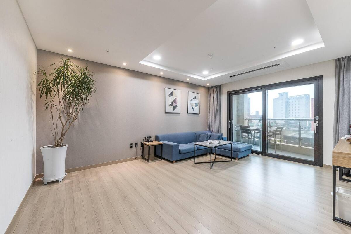 A modern living room with a blue sofa, a coffee table, and a potted plant.