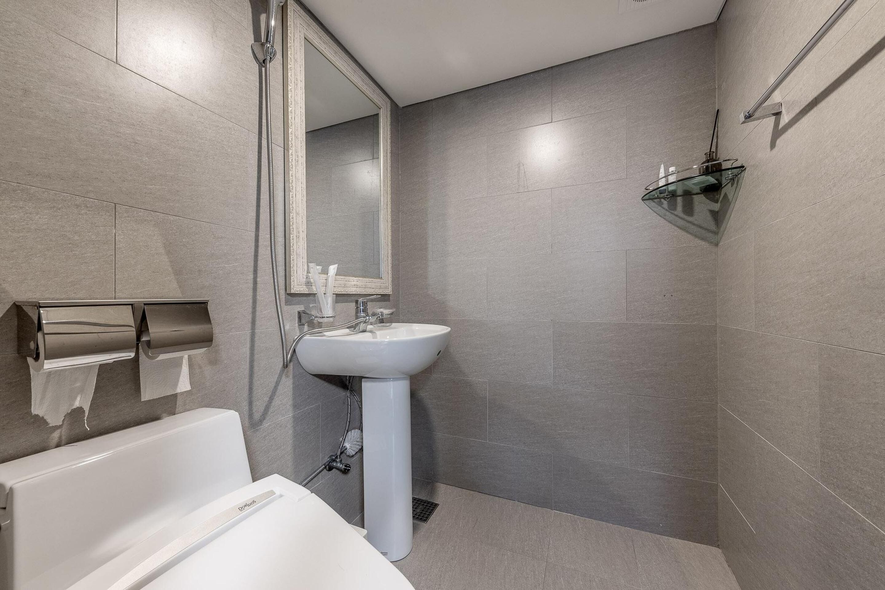 A modern bathroom with a white sink, a glass shower enclosure, and a large mirror.