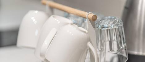 A white mug holder with a wooden handle and a clear glass mug.