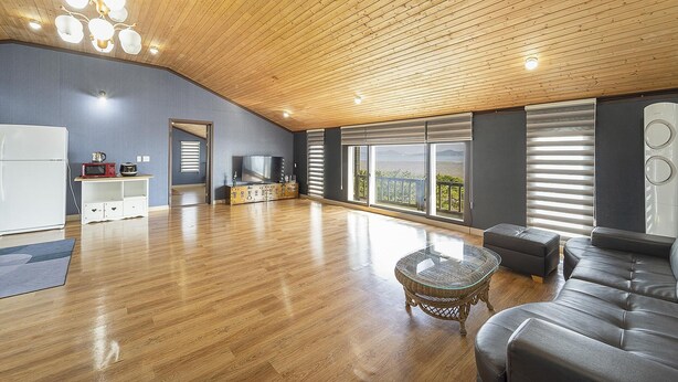 Un amplio salón con techo de madera, un televisor grande, un sofá y un balcón con vistas.