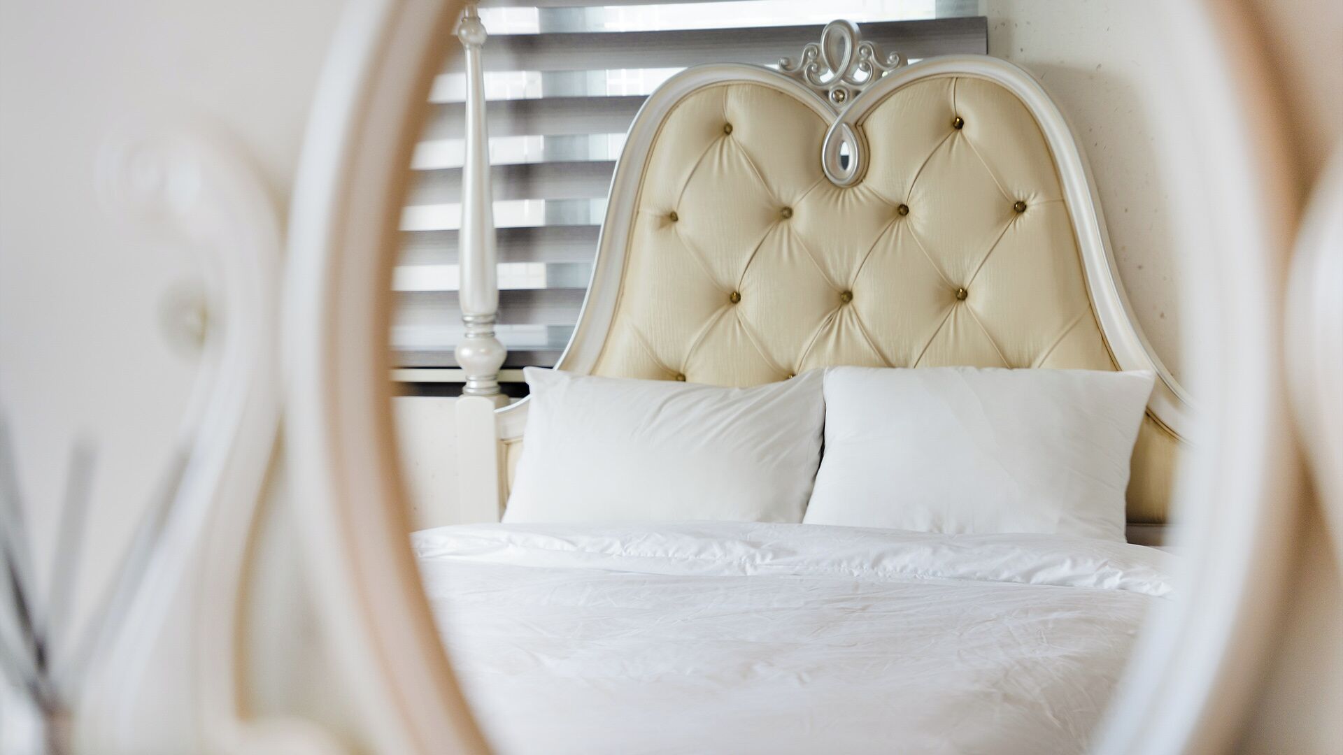 Una cama con cabecera capitonada y ropa de cama blanca.