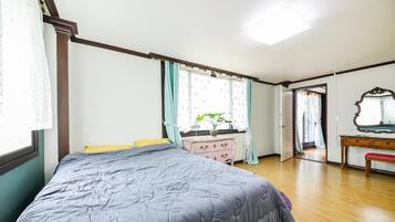 A bedroom with a bed, a dresser, a mirror, and a window with curtains.